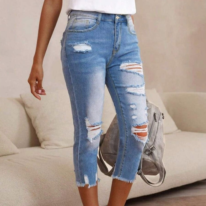 Dammjeans med sliten look, revor och råkant